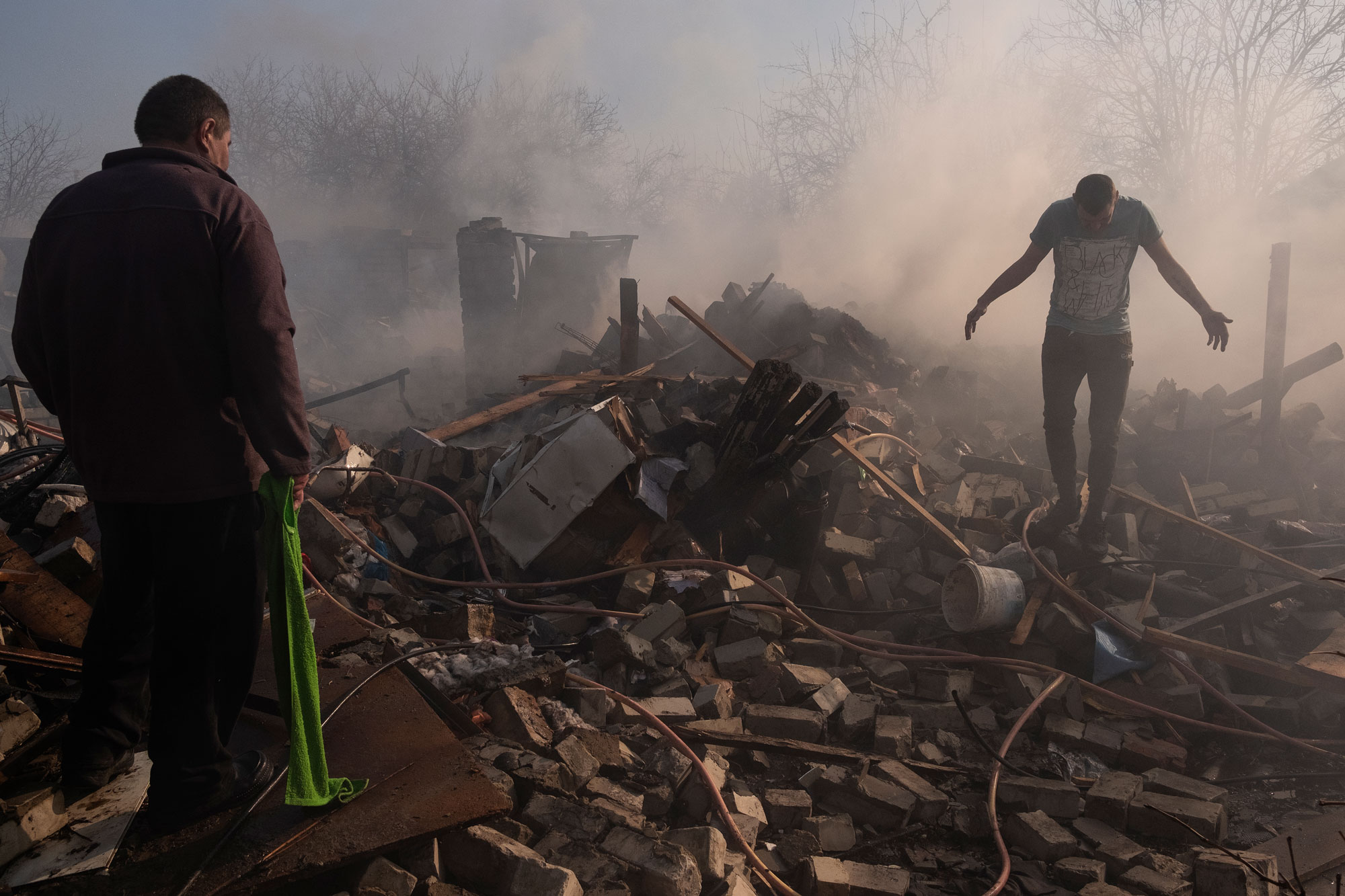 Kharkova, 24. maaliskuuta 2022. Kaksi miestä kävelee venäläisen ohjuksen tuhoaman talonsa raunioissa Harkovin Saltivkan asuinalueella. Alue on vaurioitunut pahoin Ukrainan ja Venäjän taisteluissa. Kuva: Giulio Piscitelli
